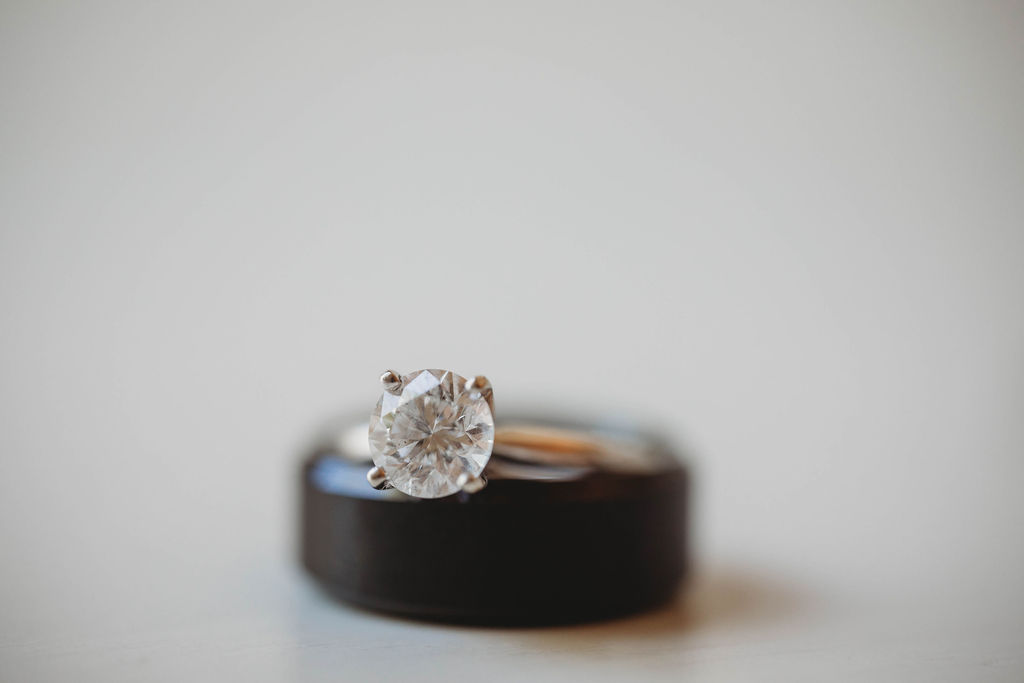 A close-up image of a diamond engagement ring stacked on top of a plain band with a soft-focus white background.