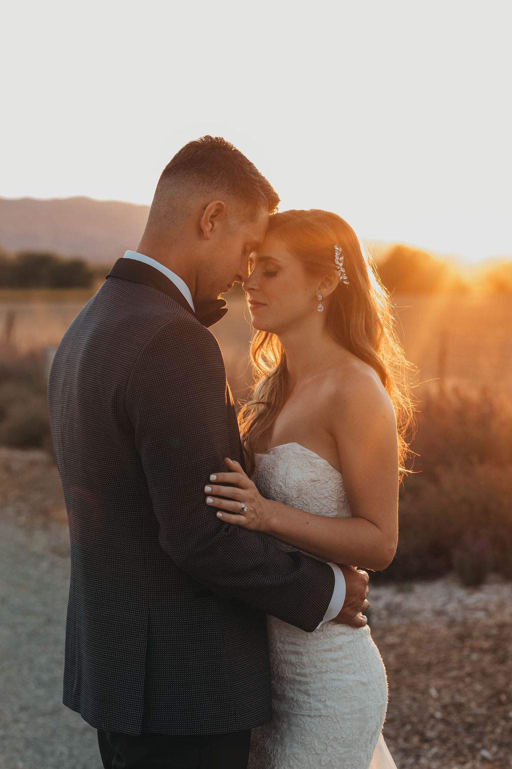A bride and groom share a tender embrace outdoors in soft sunset lighting at Park Winters wedding venue