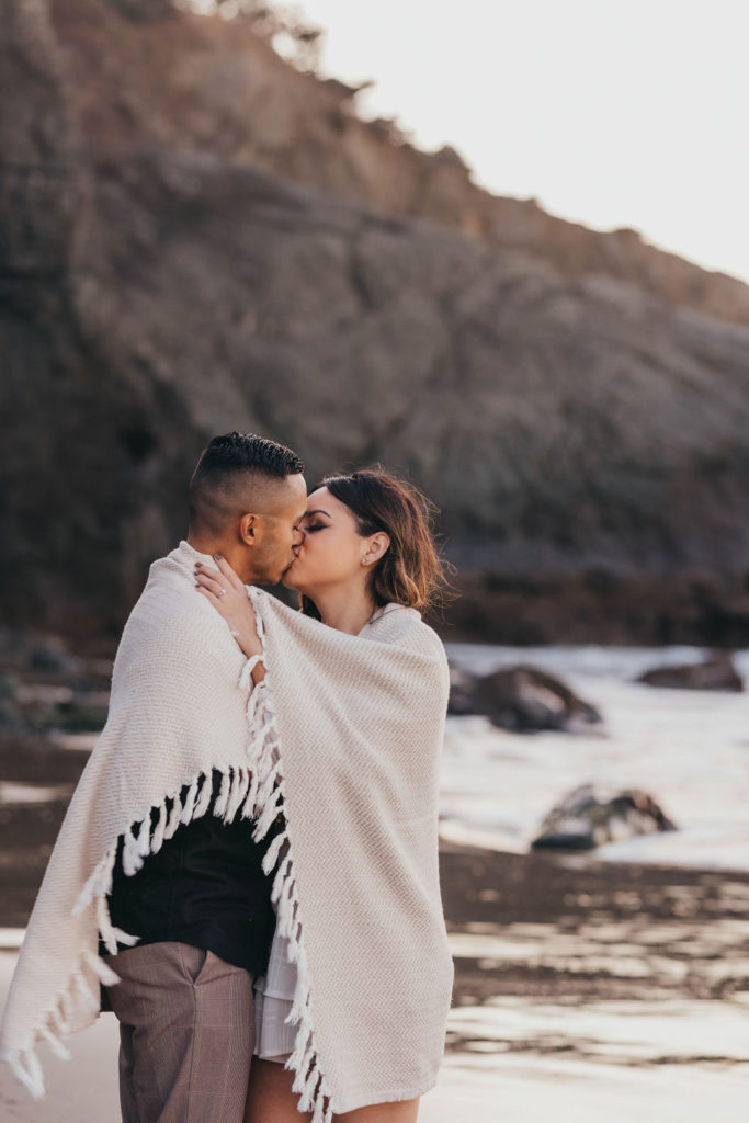 newly engaged couple kissing on the beach