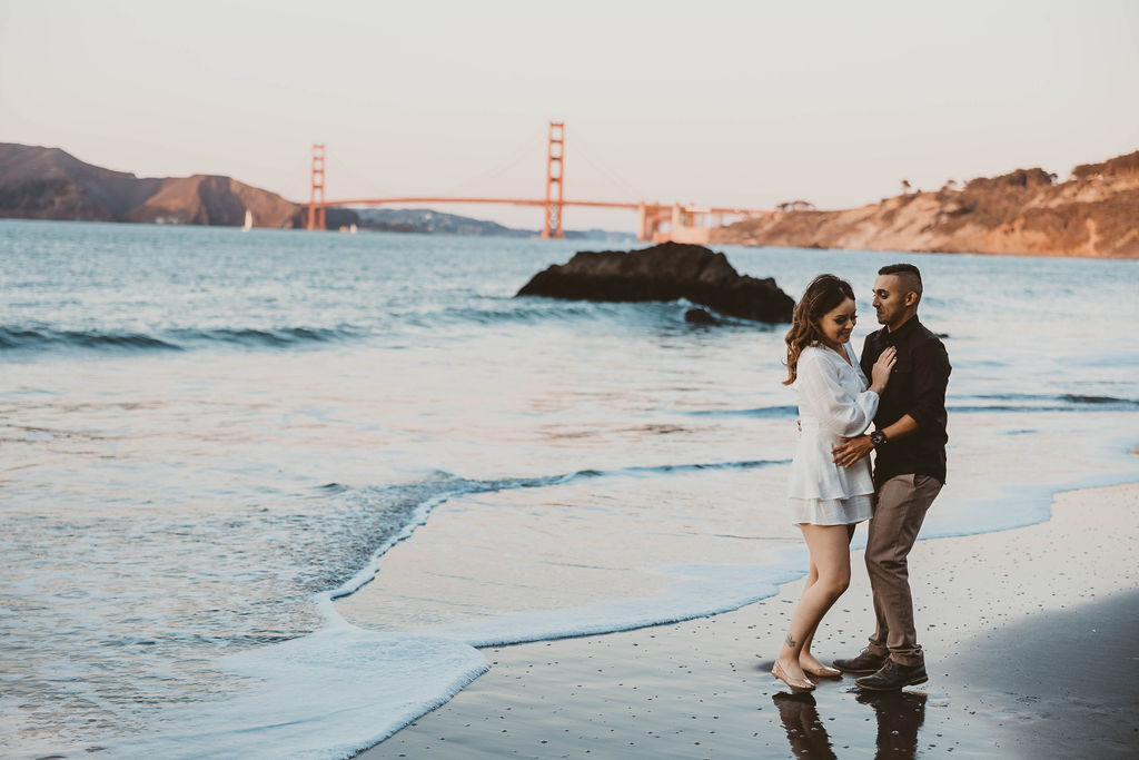 Newly engaged couple posing on China Beach in San Francisco California