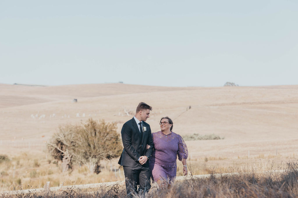 Groom and mother walking down wedding aisle