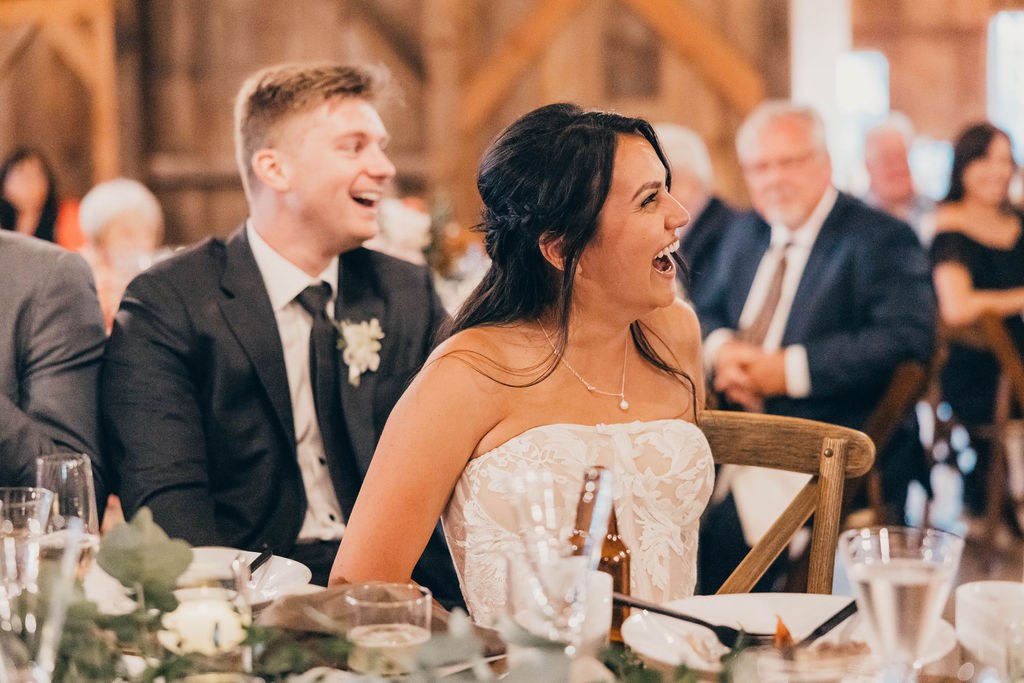 Bride and groom laughing during wedding speeches
