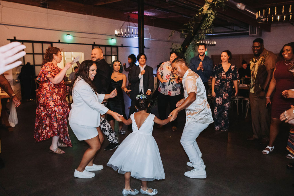 Bride and bride dancing with their children during wedding in CA reception
