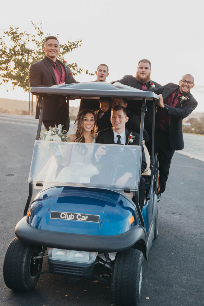 Bride, groom, and groomsman in gold cart