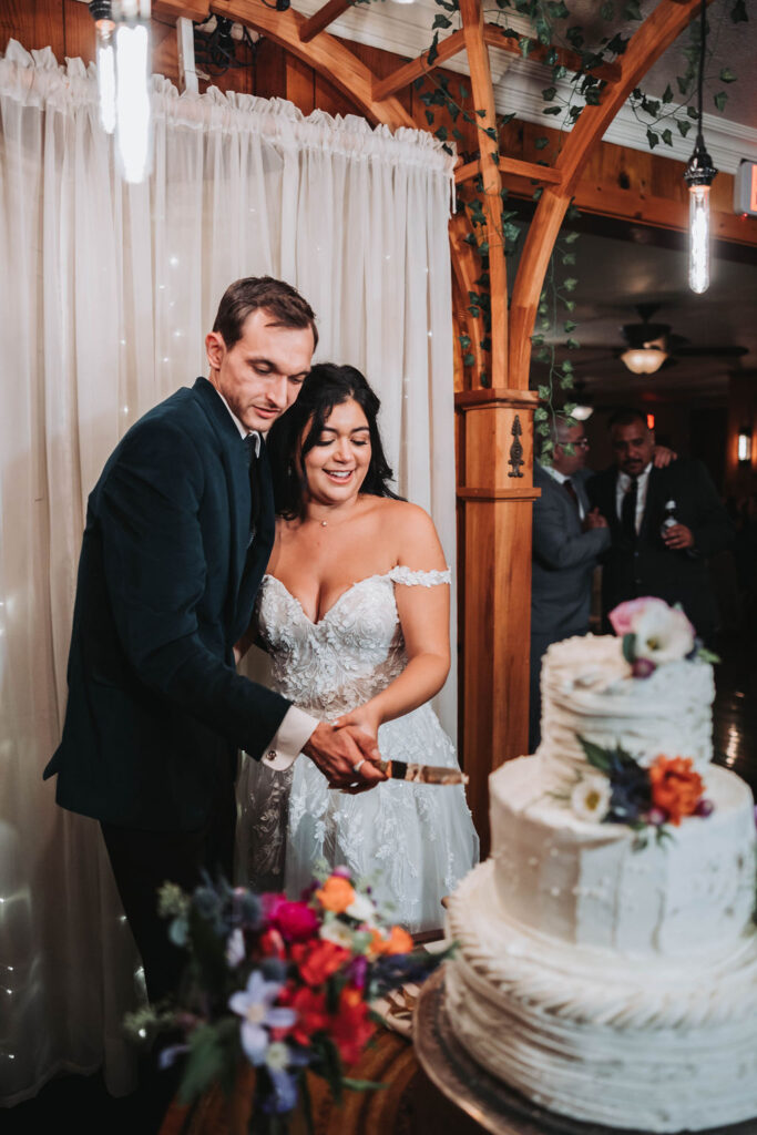 Bride and groom cutting wedding cake from jewel toned wedding