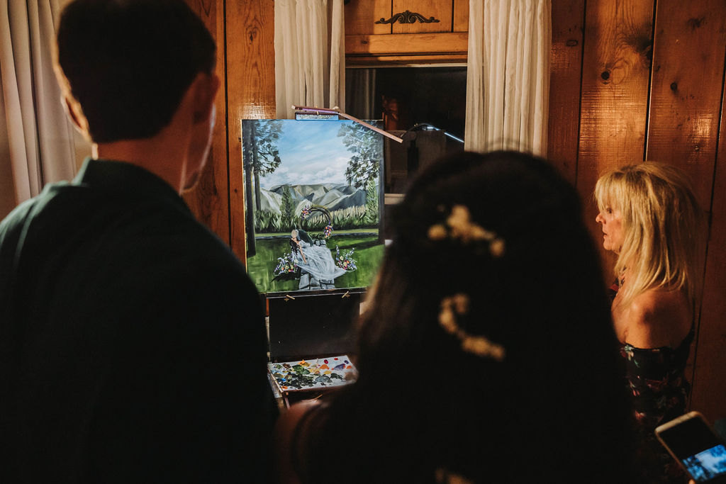 Bride and groom looking at live wedding painting 