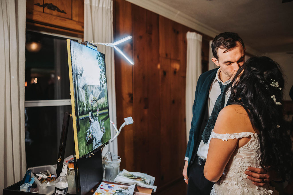 Bride and groom looking at live wedding painting 
