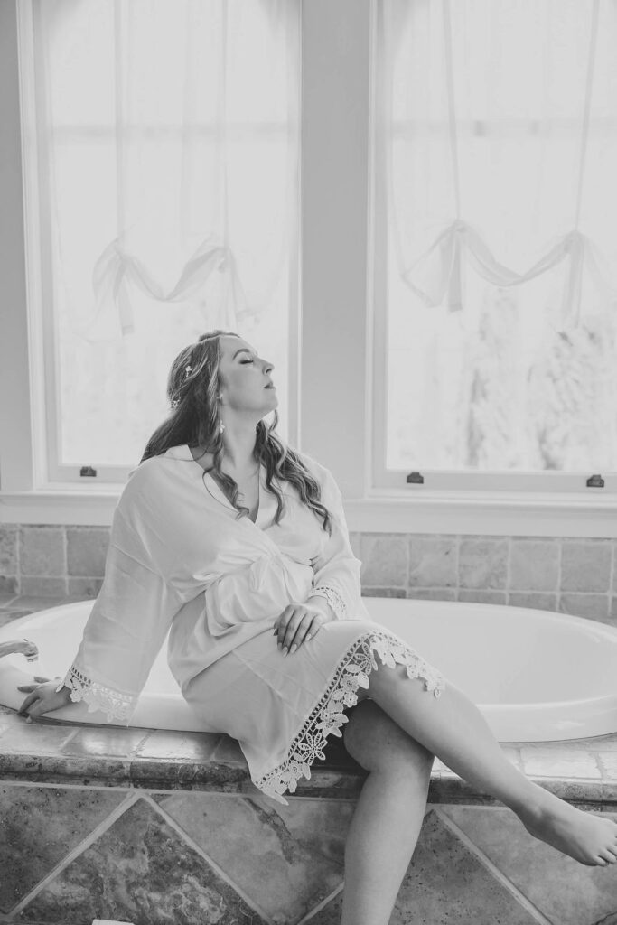 Bride sitting on bathtub in her robe