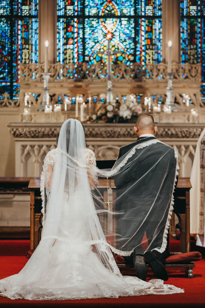 Bride and groom kneeling during catholic church wedding ceremony