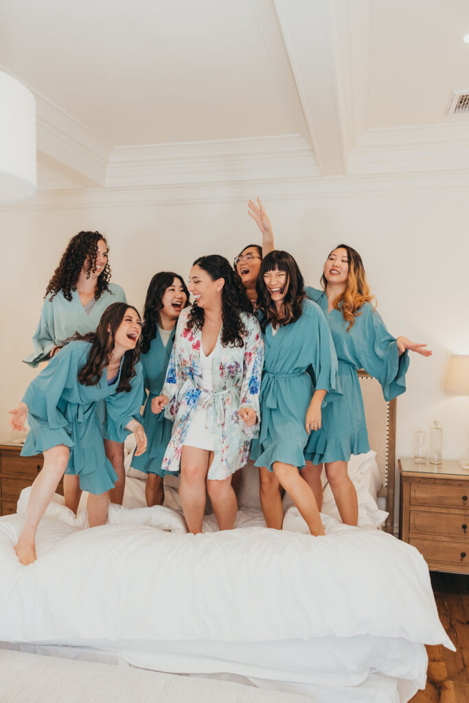 Bride and bridesmaids jumping on bed